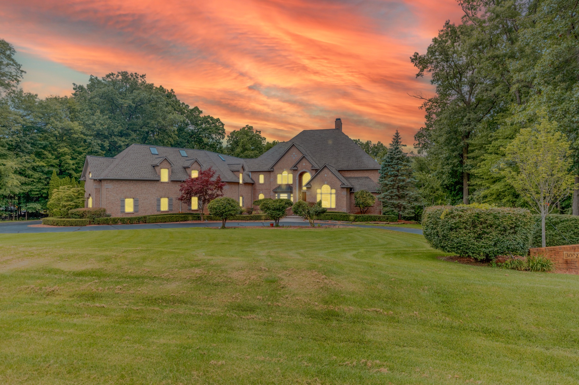 Edited exterior photograph with an orange sunset and illuminated windows